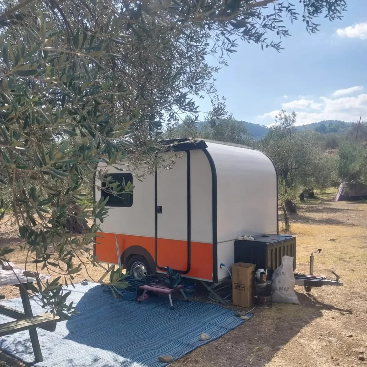 Arkasında dağlar görünen karavan