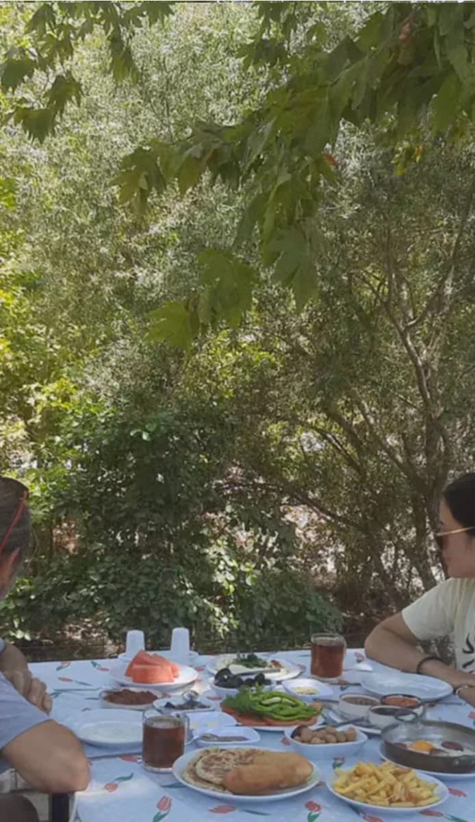 Ağaçların altında kurulmuş kahvaltı sofrası